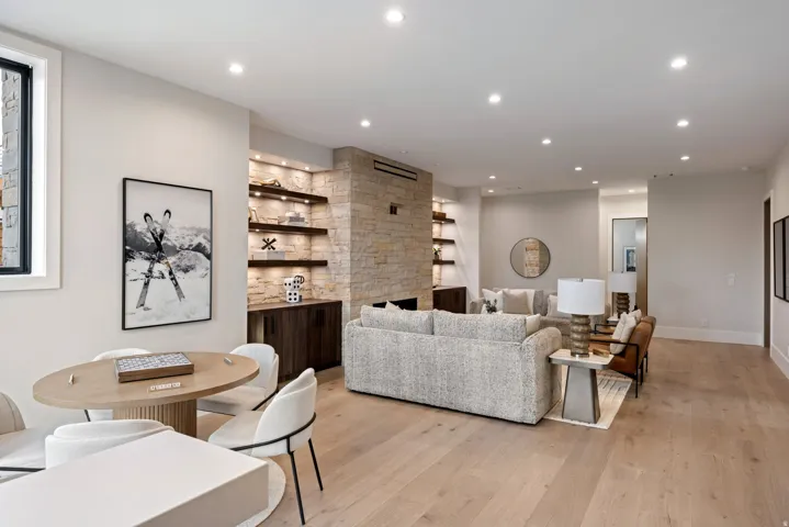 Open-concept living space featuring wood-finish flooring, recessed lighting, and a stone-clad fireplace