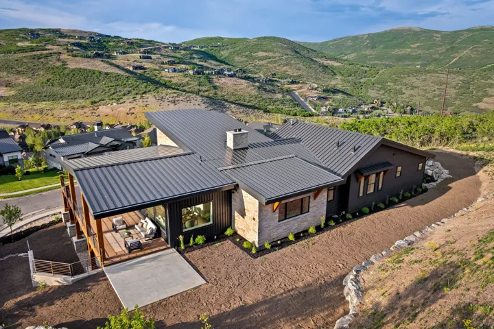 Contemporary residence featuring a dark metal roof, stone facade accents, and expansive windows
