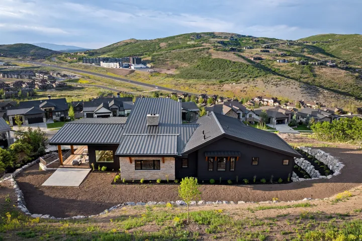 Contemporary architecture featuring dark siding, stone accents, and a standing seam metal roof