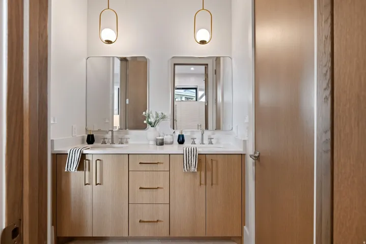 Dual vanity with light wood-finish cabinetry, white countertop, and integrated sinks