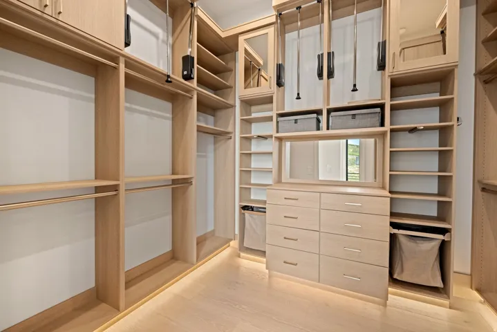 Custom closet system with light wood-finish cabinetry, integrated drawers, and adjustable shelving