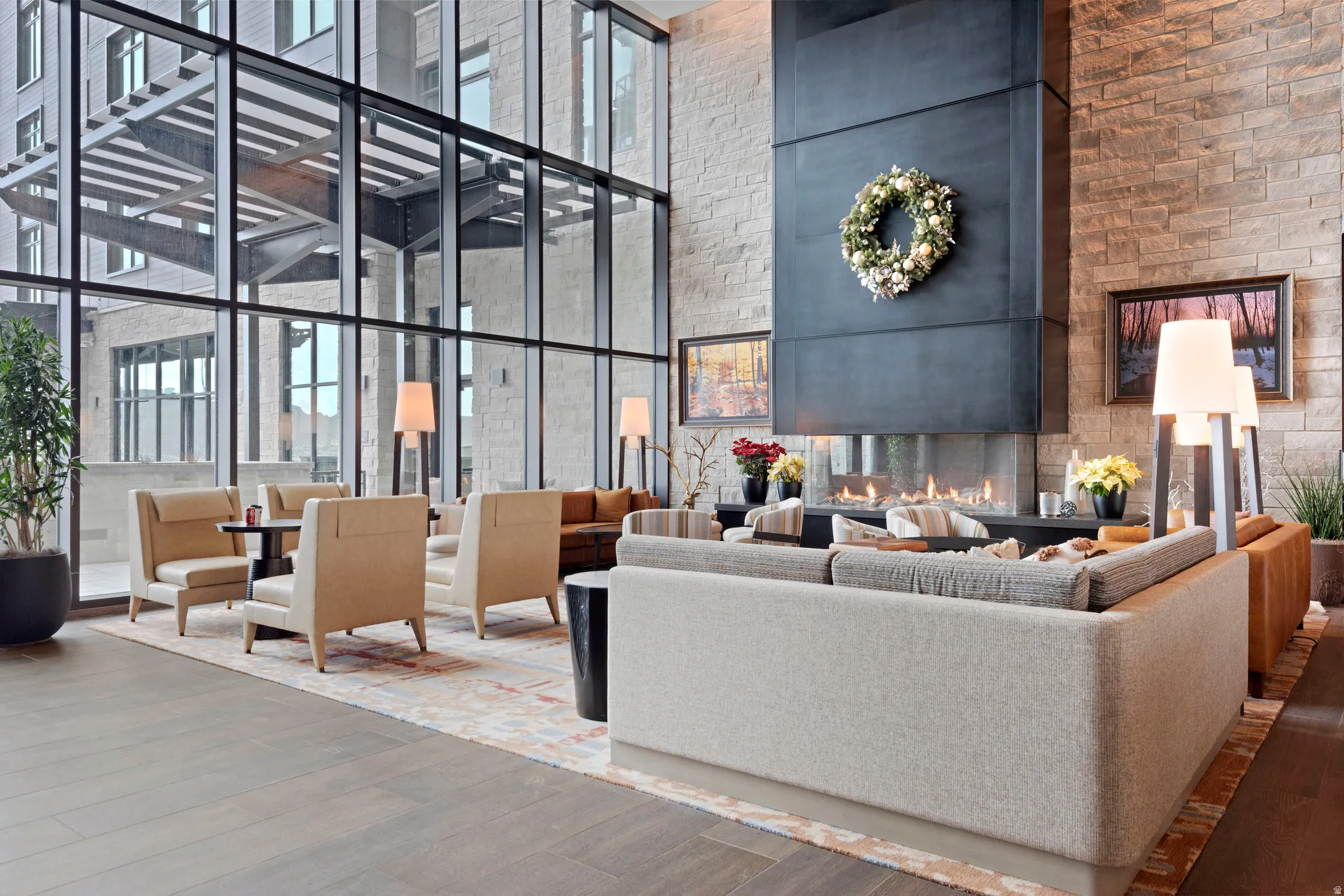 Expansive common area featuring a floor-to-ceiling glass wall, a multi-sided built-in fireplace with a dark metal surround, and stone accent walls