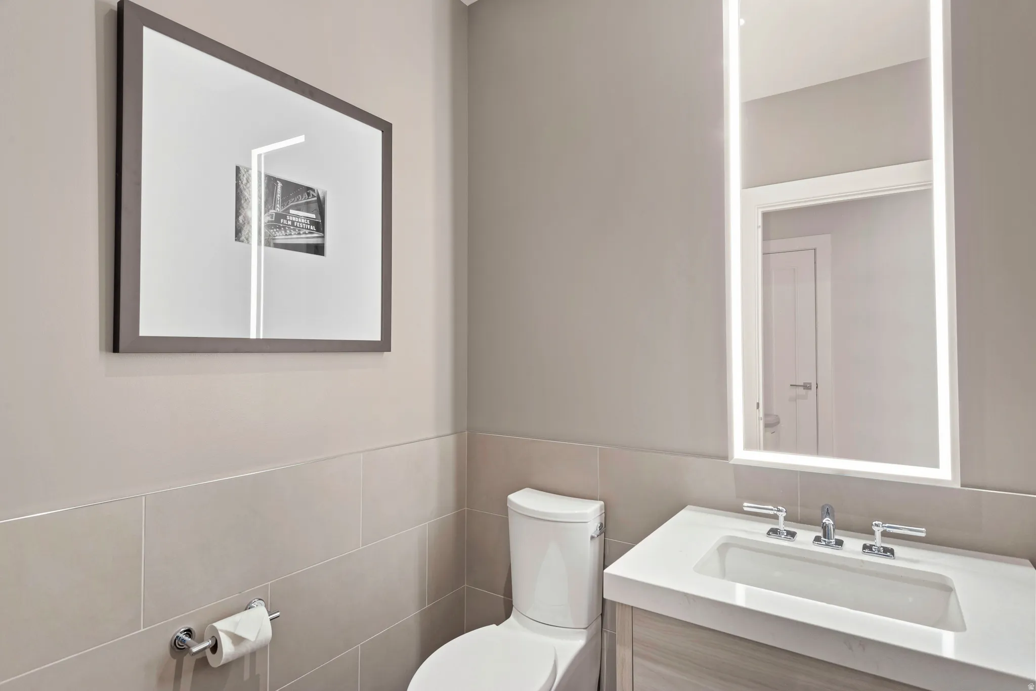 Modern powder room featuring a floating wood-finish vanity with an integrated sink and chrome fixtures