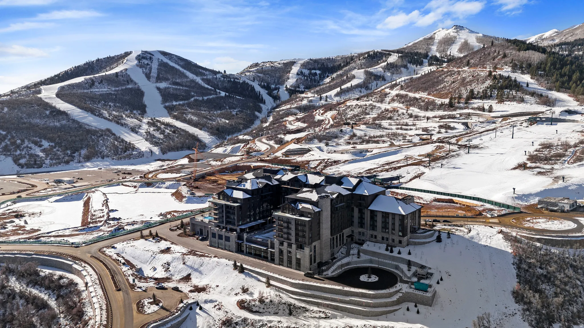 Expansive alpine setting featuring a large building complex with multiple levels and a substantial driveway
