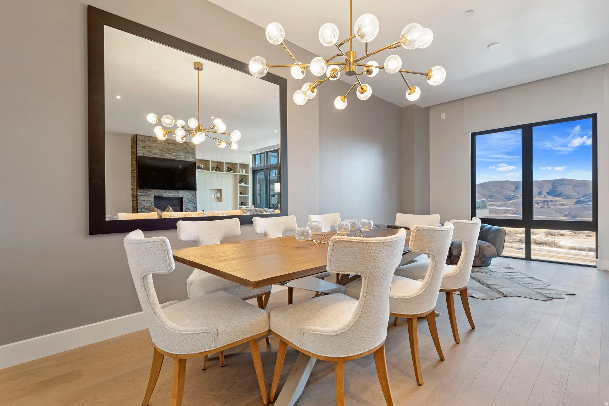 Dining area featuring wood-finish flooring, a large framed mirror, and a modern chandelier