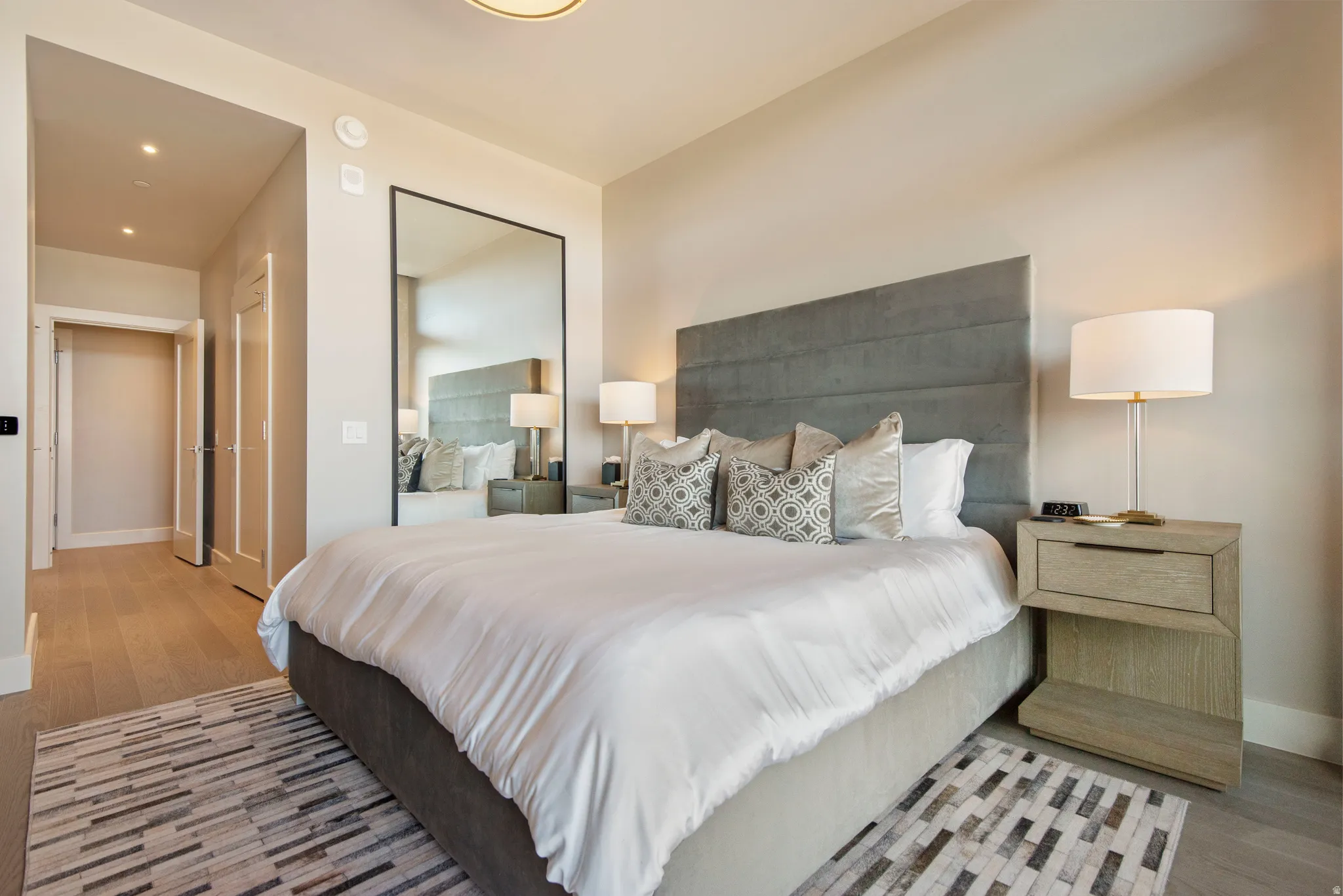 Spacious room featuring wood-finish flooring, recessed lighting, and a full-length mirror