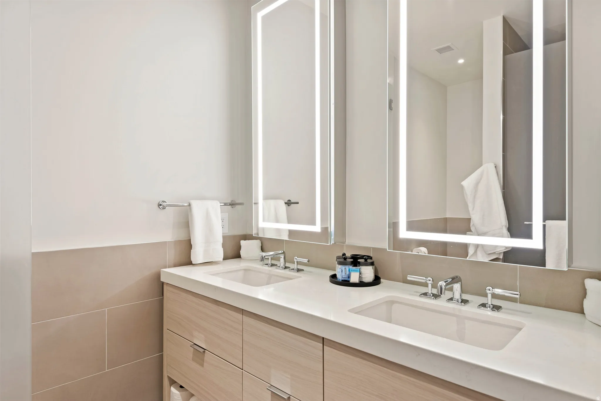 Dual vanity with integrated sinks, light wood-finish cabinetry, and white countertops