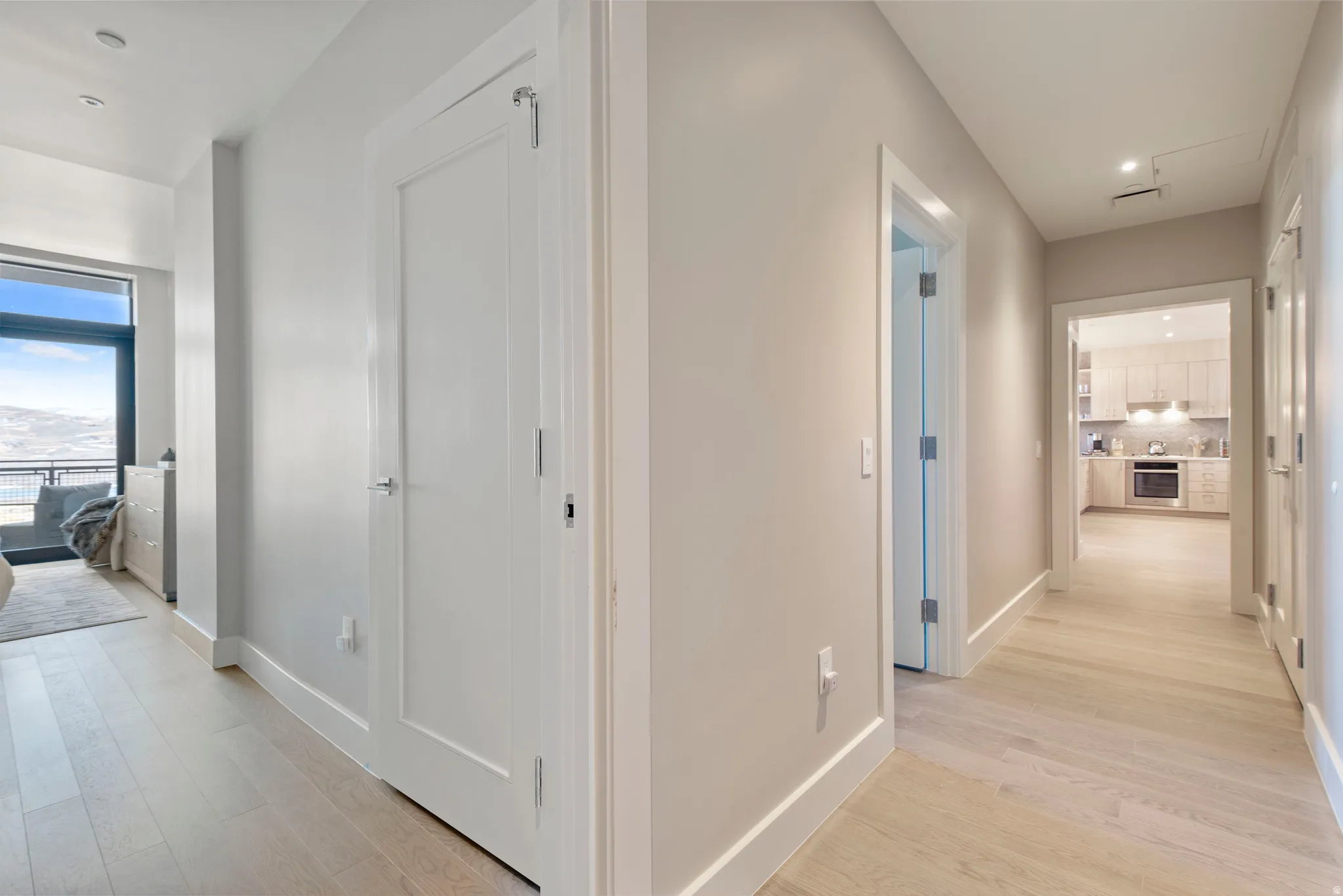 Hallway featuring light wood-finish flooring, recessed lighting, and white baseboards