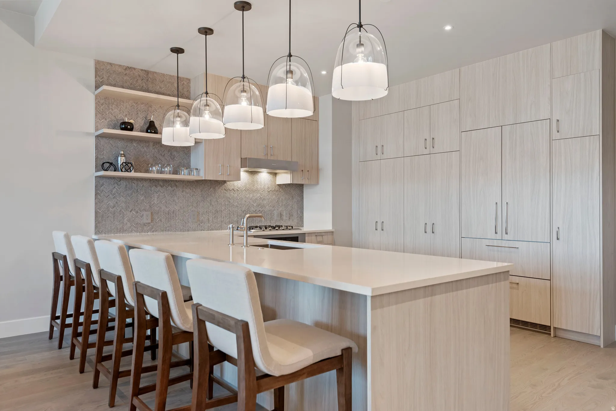Spacious kitchen featuring an extended island with seating, integrated appliances, extensive cabinetry, and pendant lighting fixtures