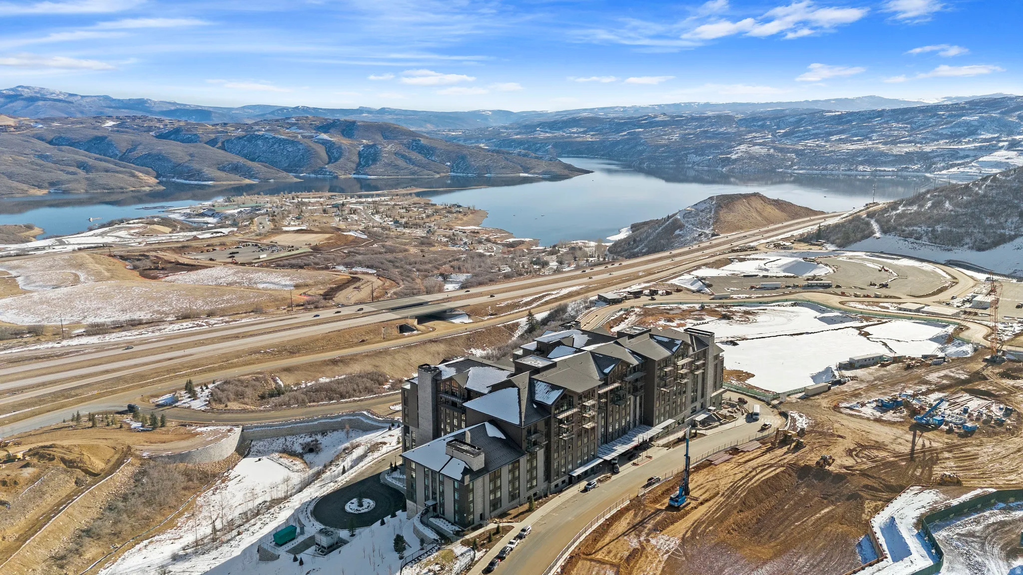Multi-story building featuring stone and dark siding, set against a backdrop of distant mountains and a large body of water