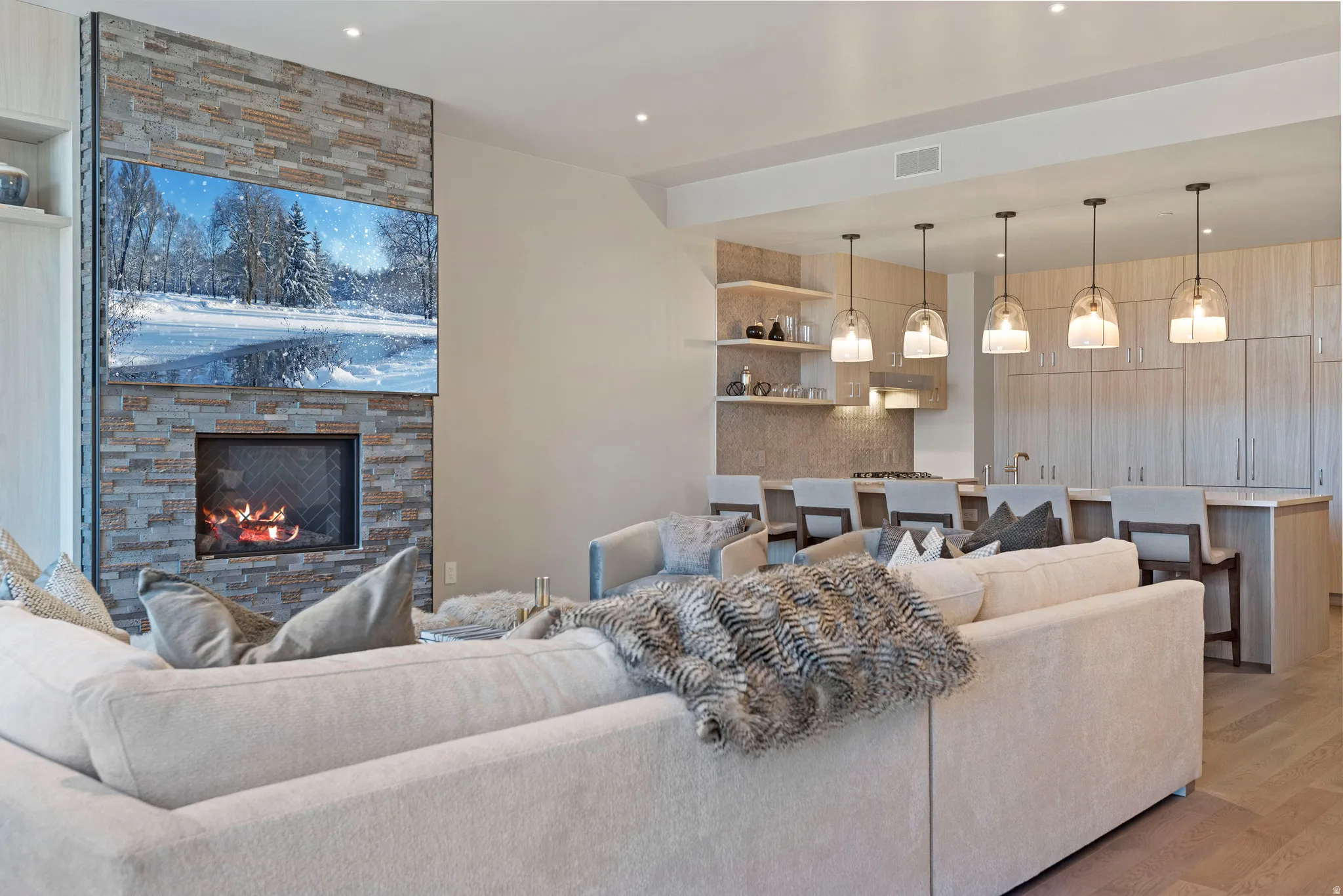 Open-concept living space featuring a stacked stone fireplace with an integrated television
