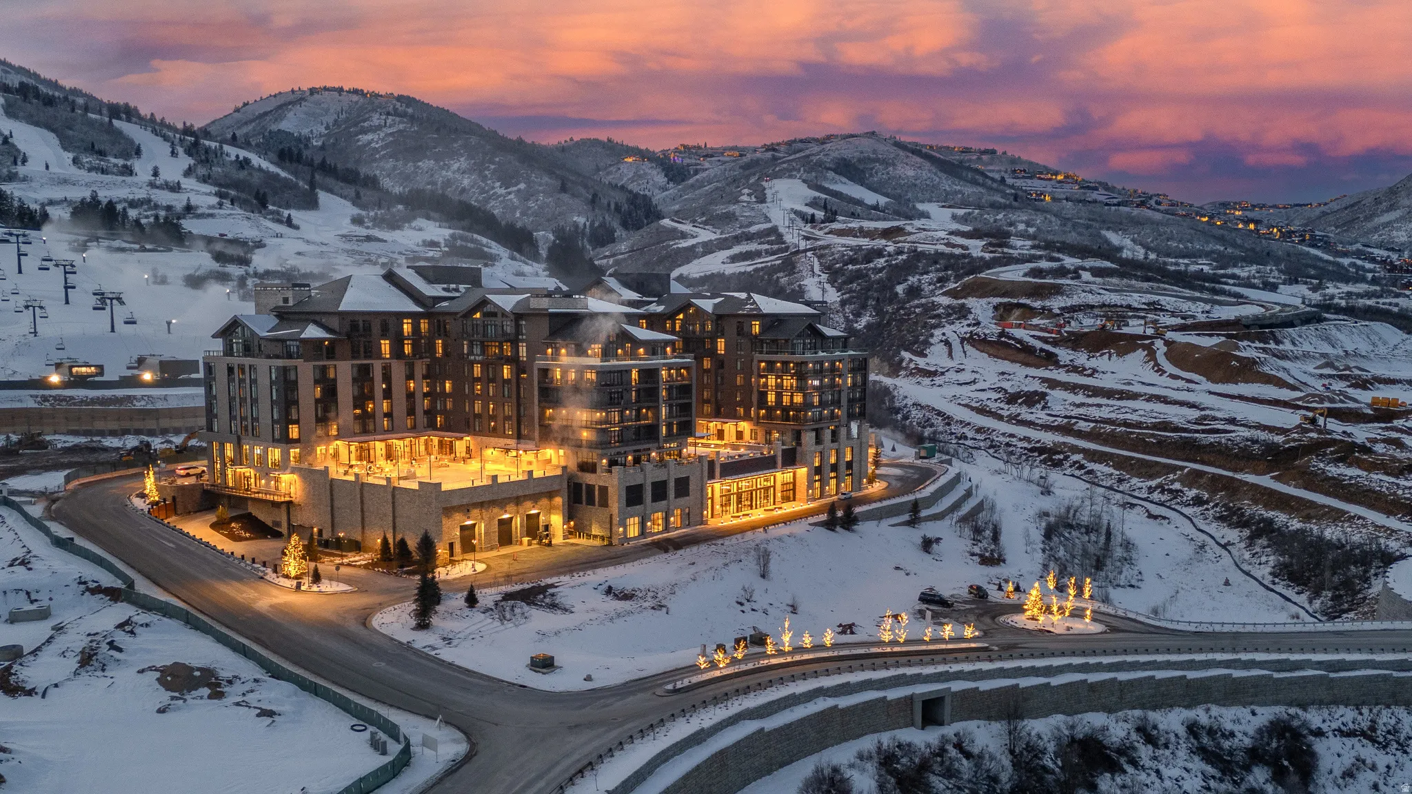 Multi-story building featuring illuminated architecture, stone and wood-tone facade elements, and expansive outdoor terrace spaces
