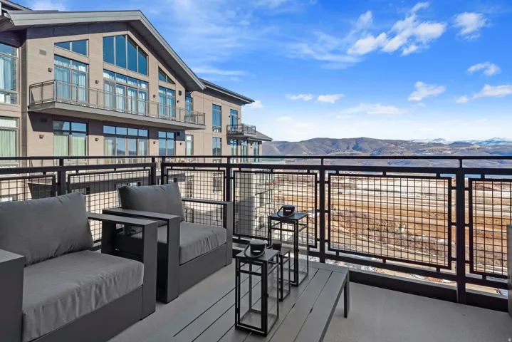 Private balcony with composite decking and a black metal railing, featuring expansive mountain scenery