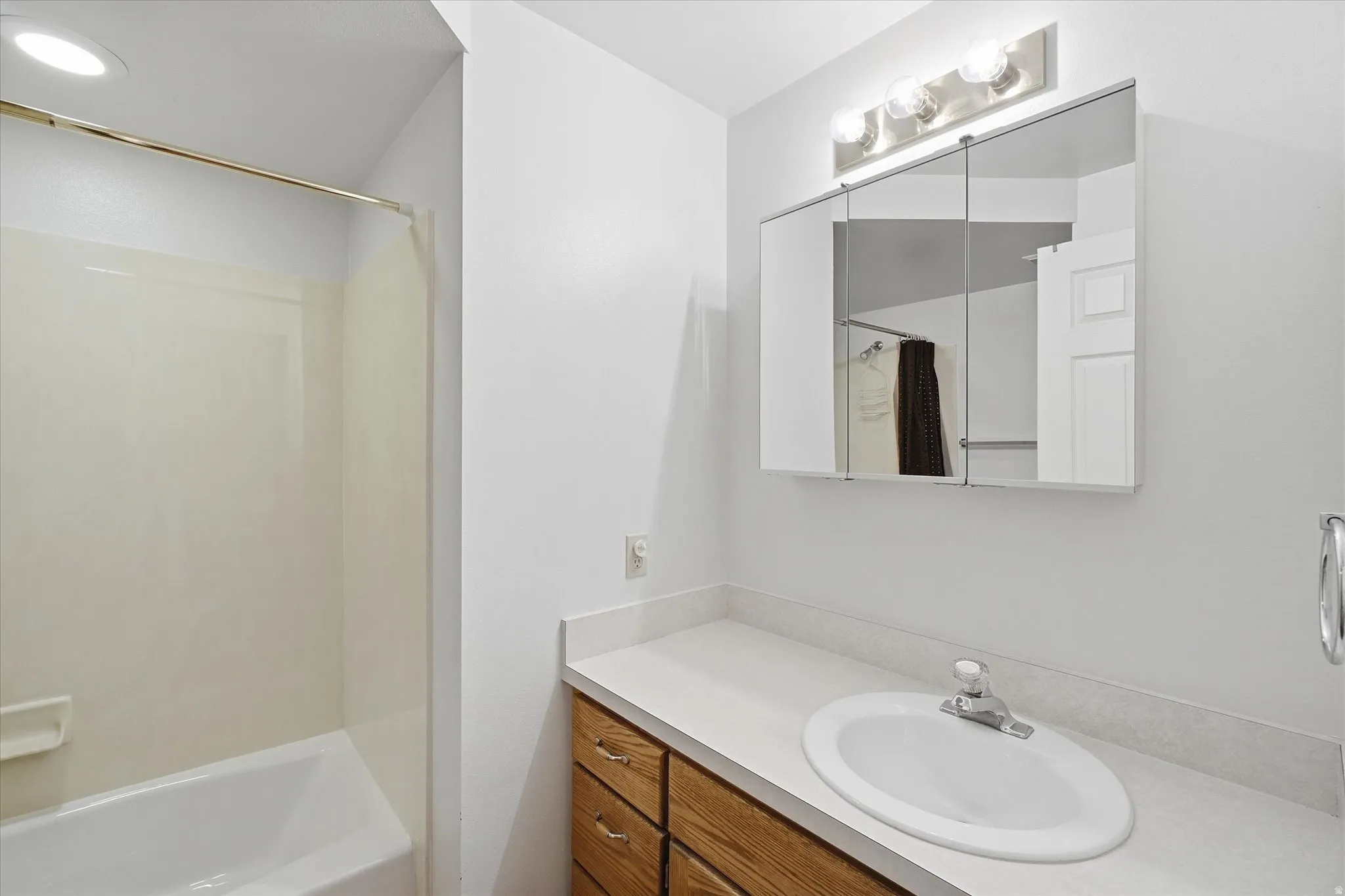 Bathroom featuring a built-in vanity with a laminate countertop, an oval undermount sink, and wood-finish cabinetry