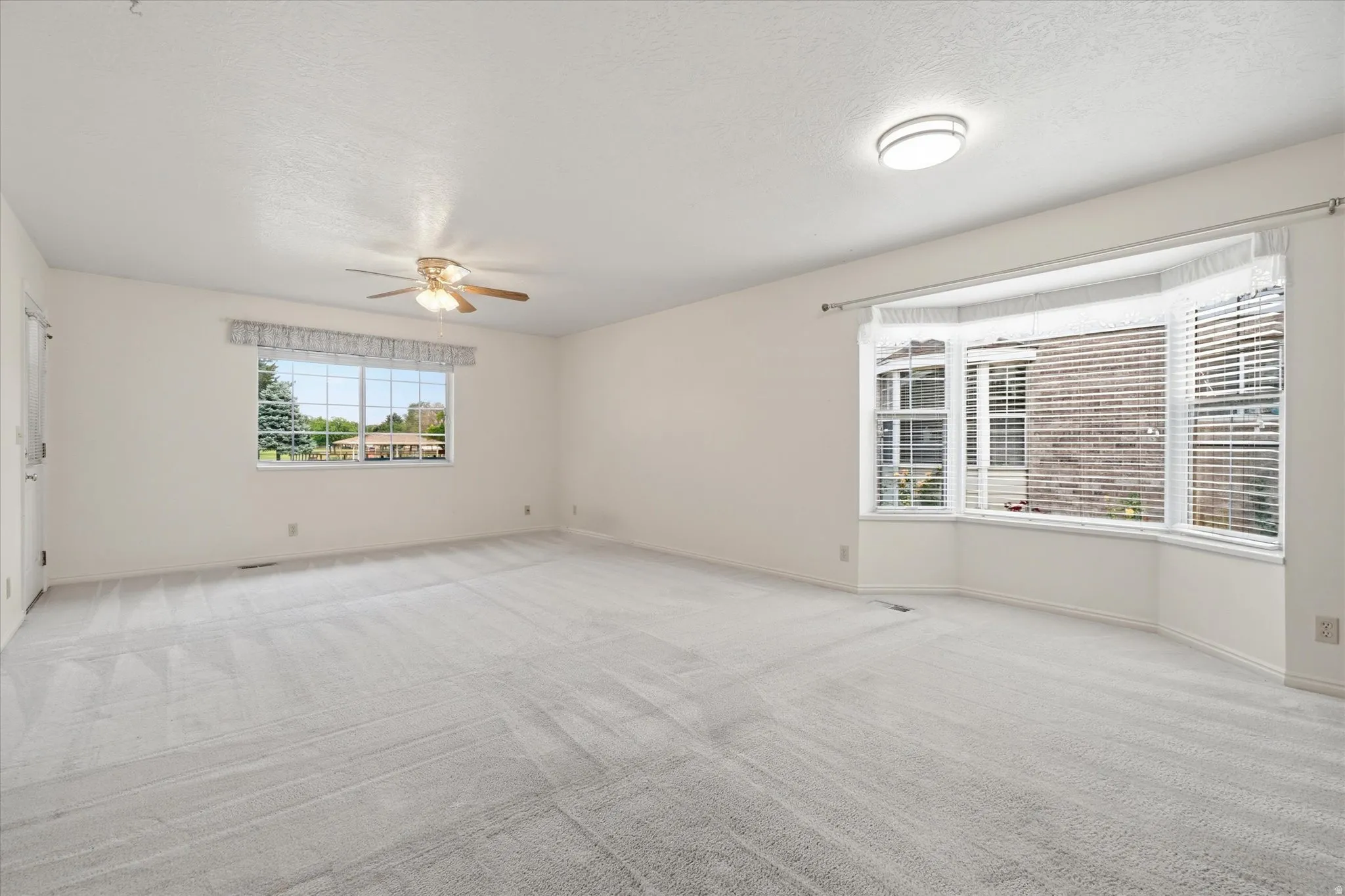Spacious interior room featuring light-toned carpeting and neutral wall finishes