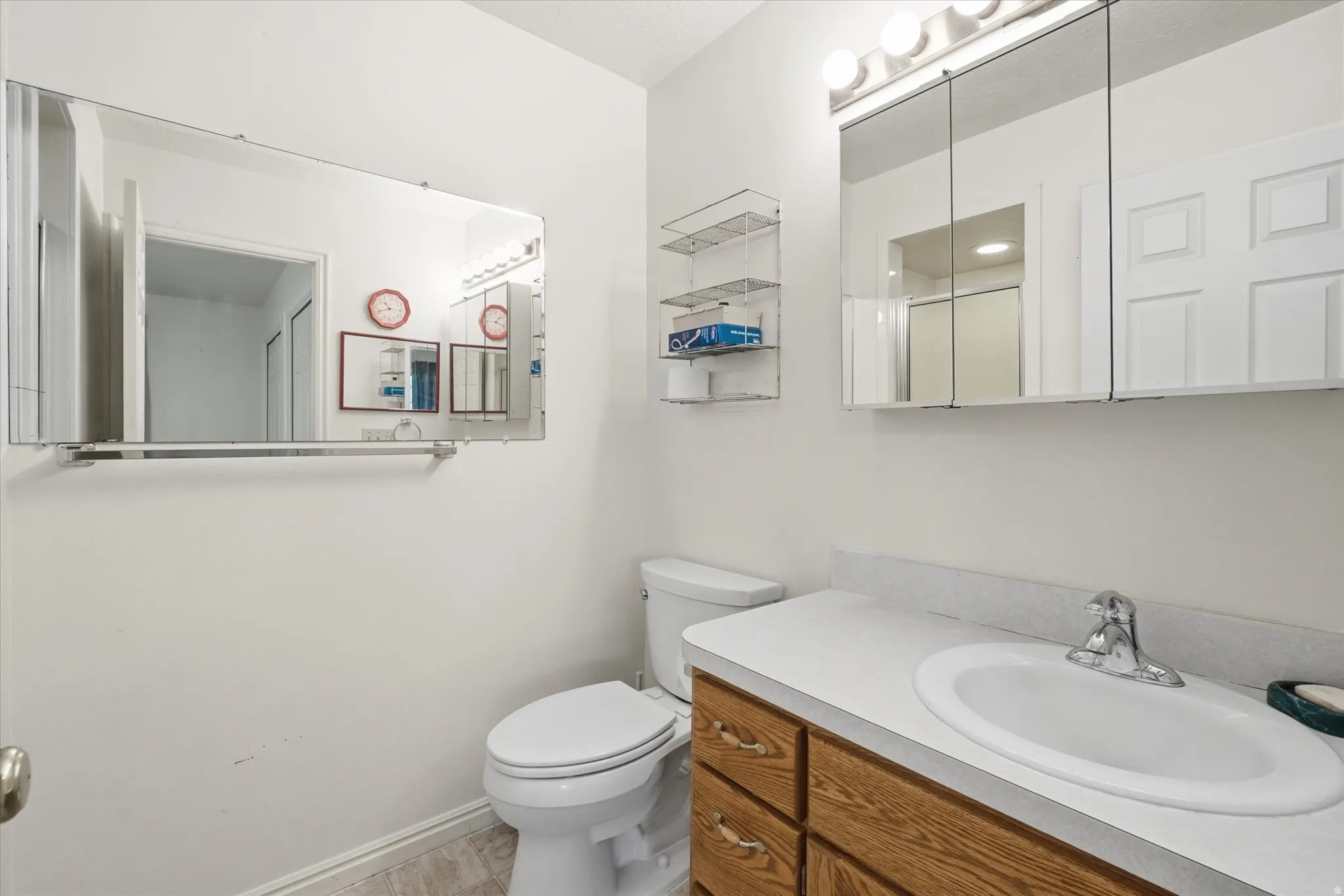 Bathroom vanity with light wood-finish cabinetry and a white countertop with an integrated sink