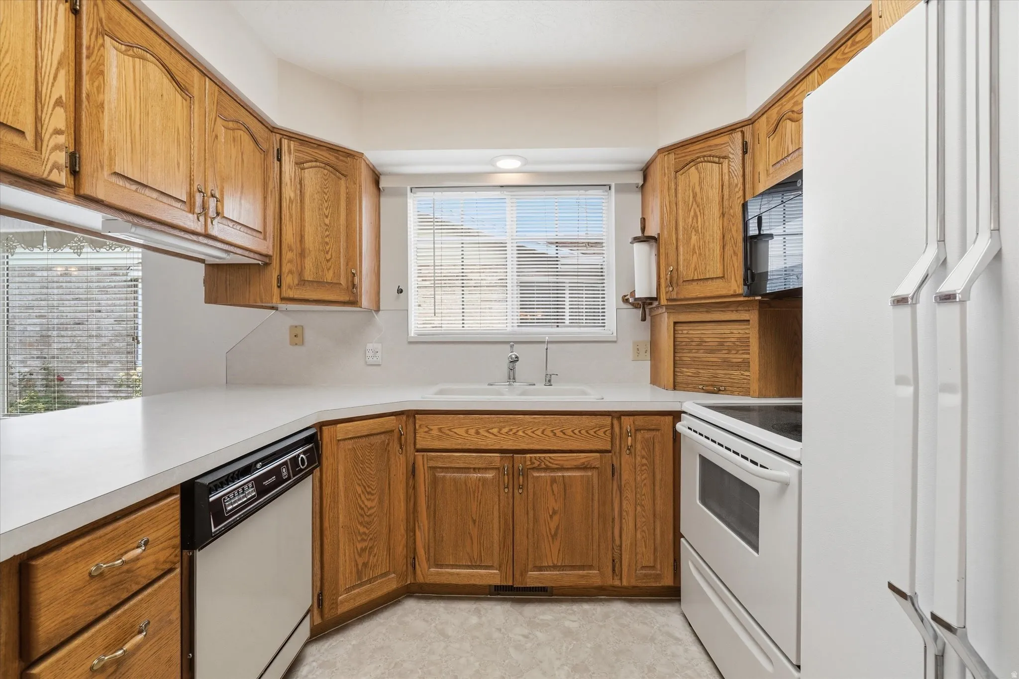 Kitchen featuring wood-finish cabinetry, white countertops, and a white sink with a chrome faucet