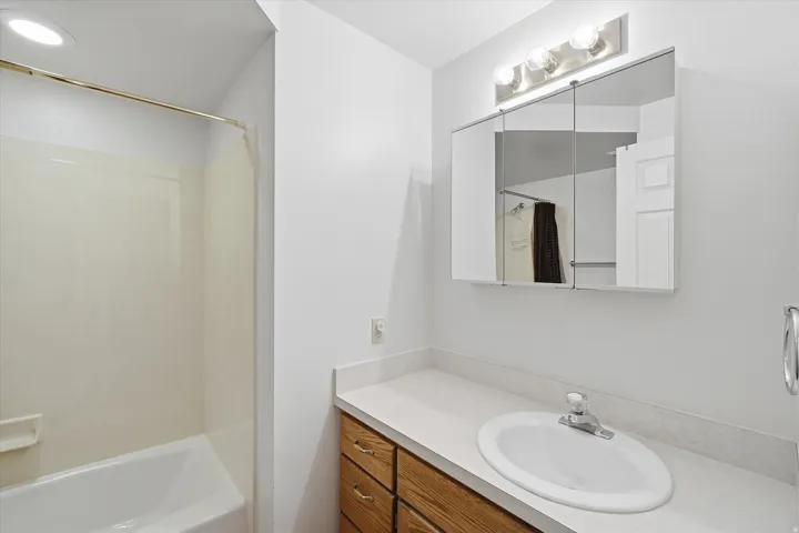 Bathroom featuring a built-in vanity with a laminate countertop, an oval undermount sink, and wood-finish cabinetry