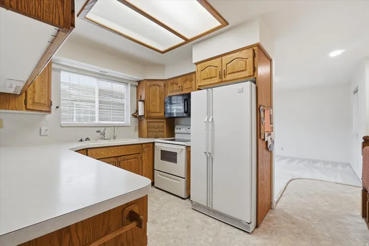 Kitchen featuring wood cabinetry, white countertops, built-in appliances, and a fluorescent ceiling light fixture