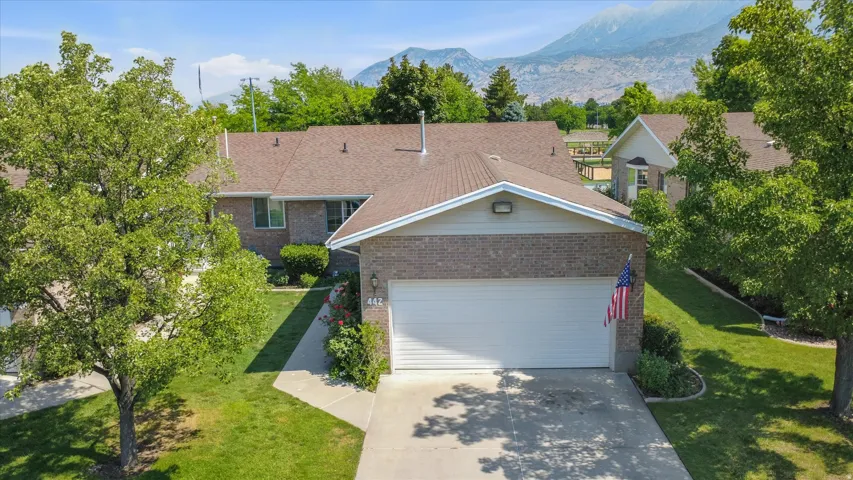 Brick exterior residence with a two-car garage, concrete driveway, and mature landscaping
