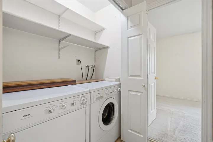Dedicated laundry area featuring a washer and dryer, upper wall shelving, and utility hookups