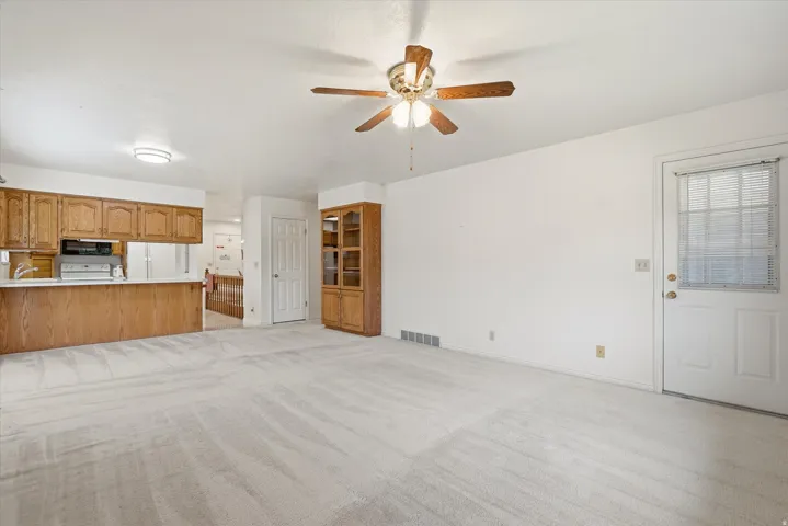 Spacious living area featuring light-toned carpeting and white walls