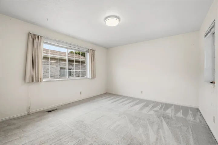 Spacious room featuring light gray carpeting and white walls