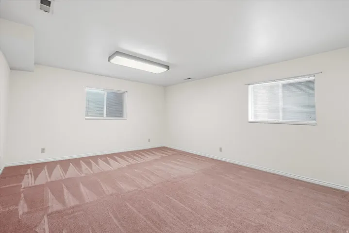 Spacious room featuring neutral white walls and a light pink carpet