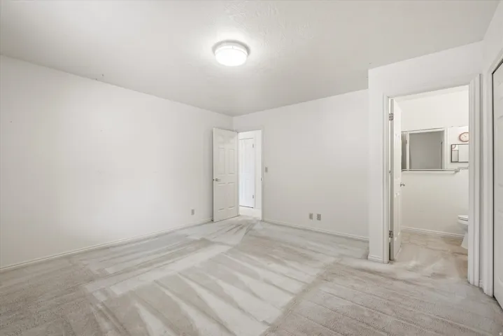 Carpeted room with a flush-mount ceiling light fixture, white walls, and white trim
