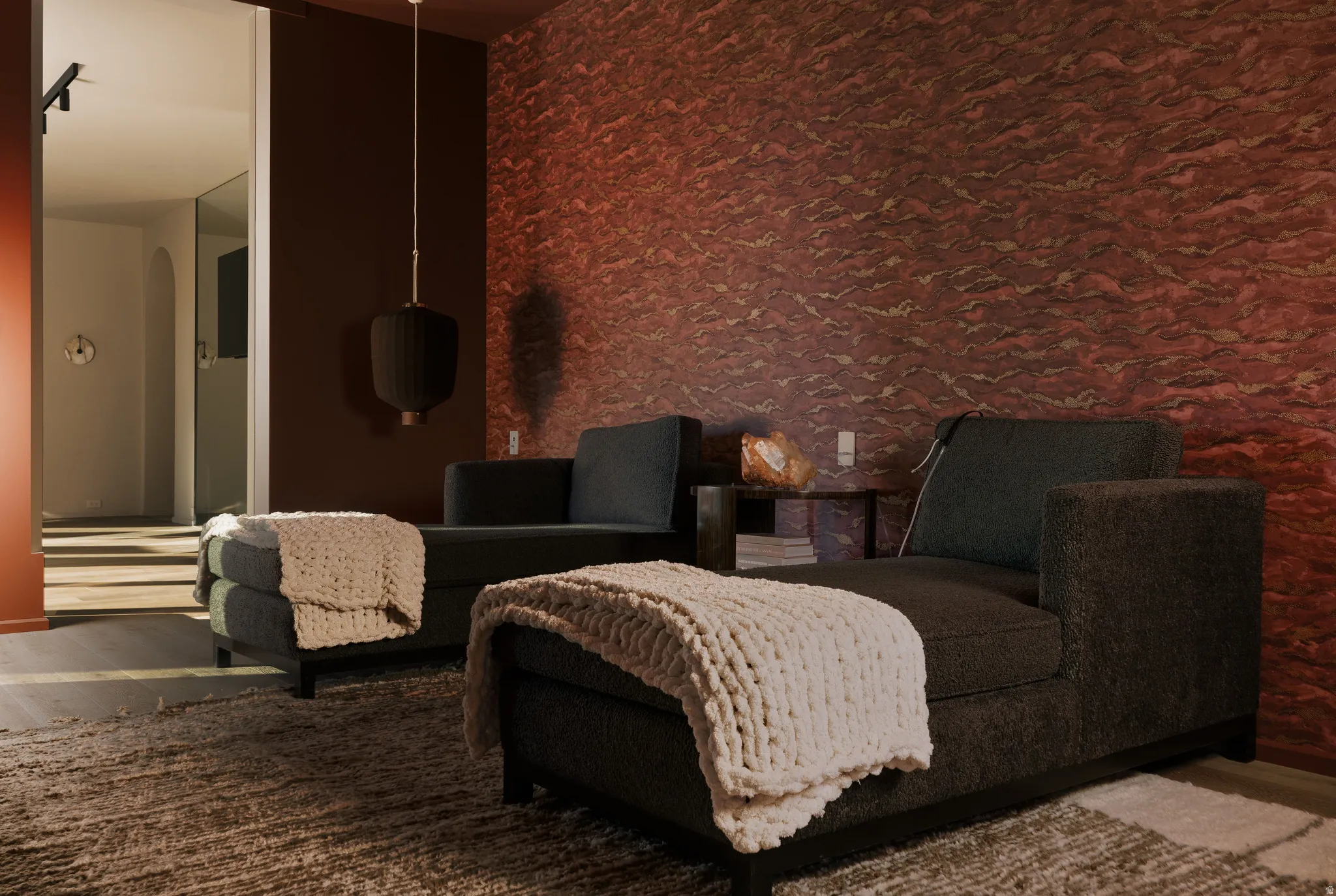 Interior space featuring a textured accent wall, dark wood-finish flooring, and a contemporary pendant light fixture