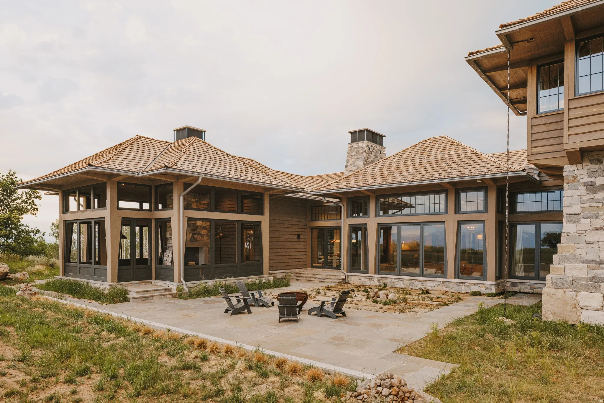 Expansive outdoor patio featuring a fire pit area, natural stone accents, and a stone-clad chimney