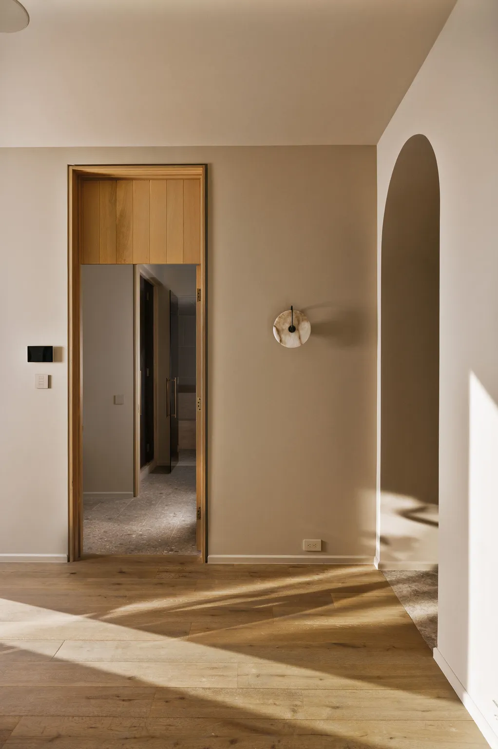 Light wood-finish flooring extending into an arched entryway