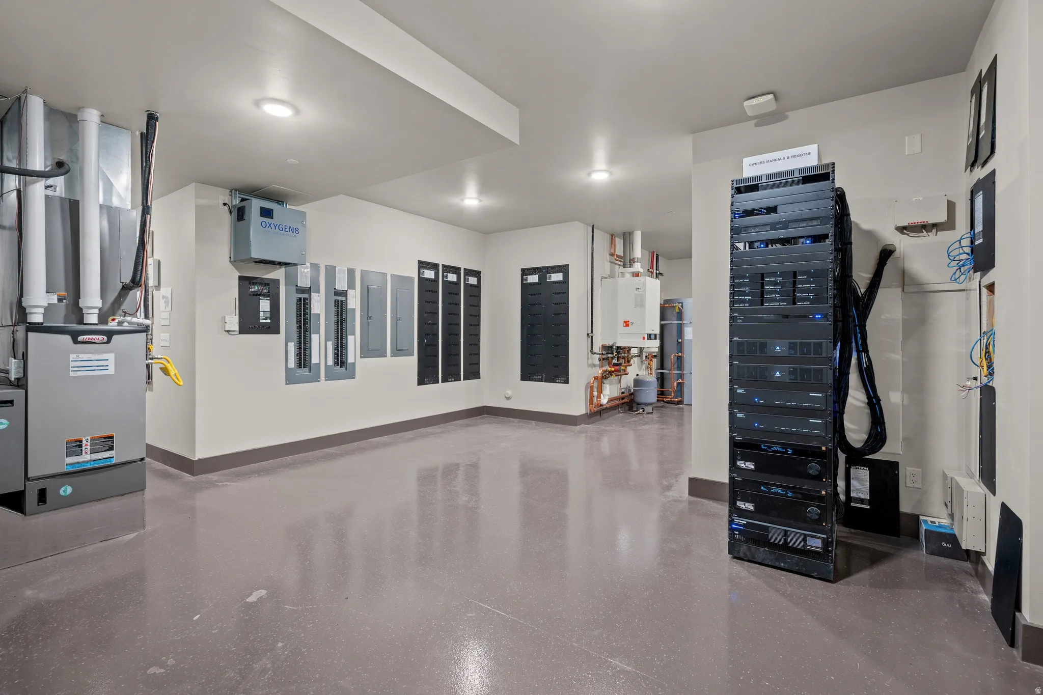 Dedicated utility room featuring a furnace, multiple electrical panels, an extensive server rack, and water heaters