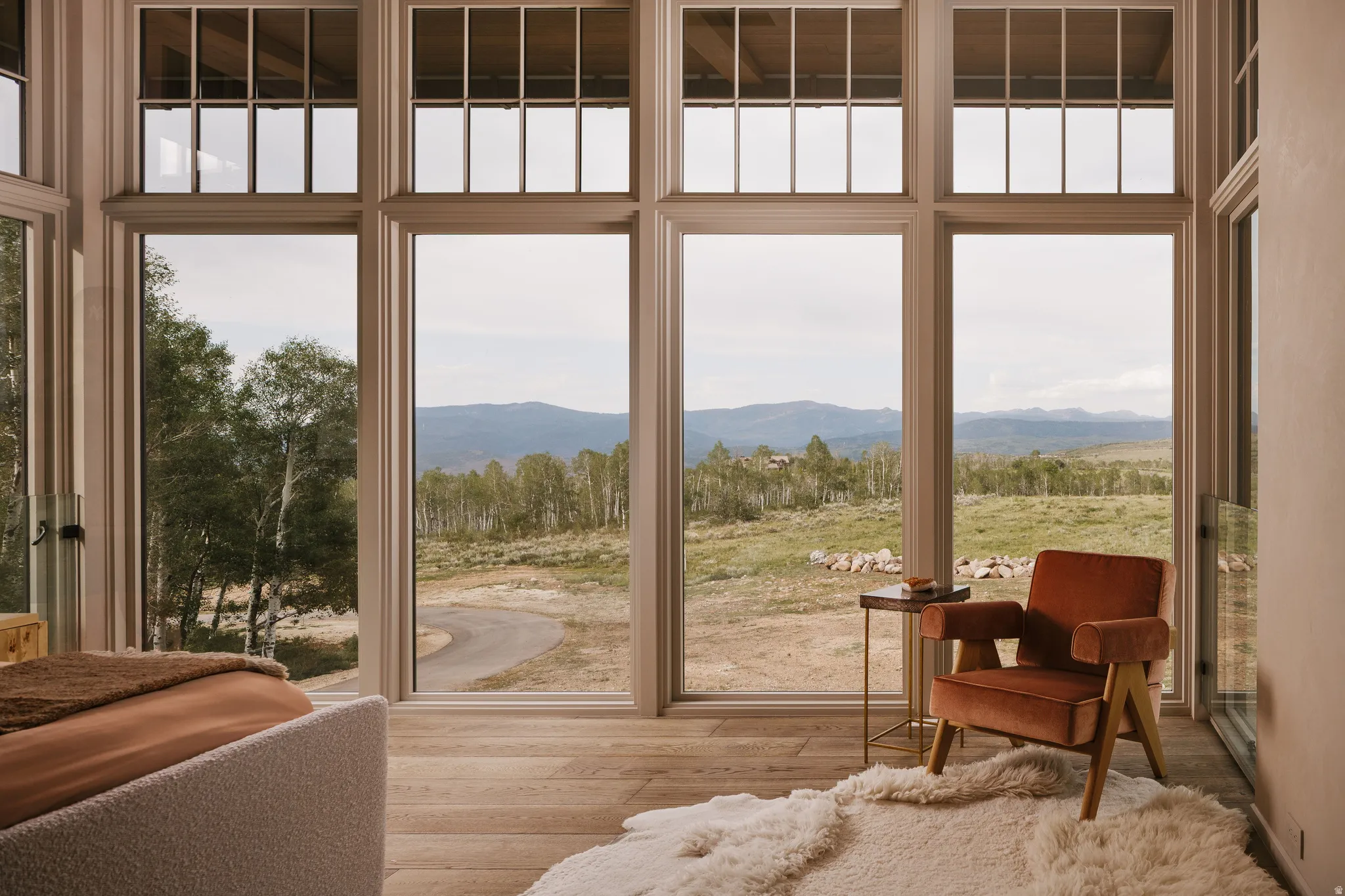 Floor-to-ceiling windows with upper transoms frame mountain and tree scenery