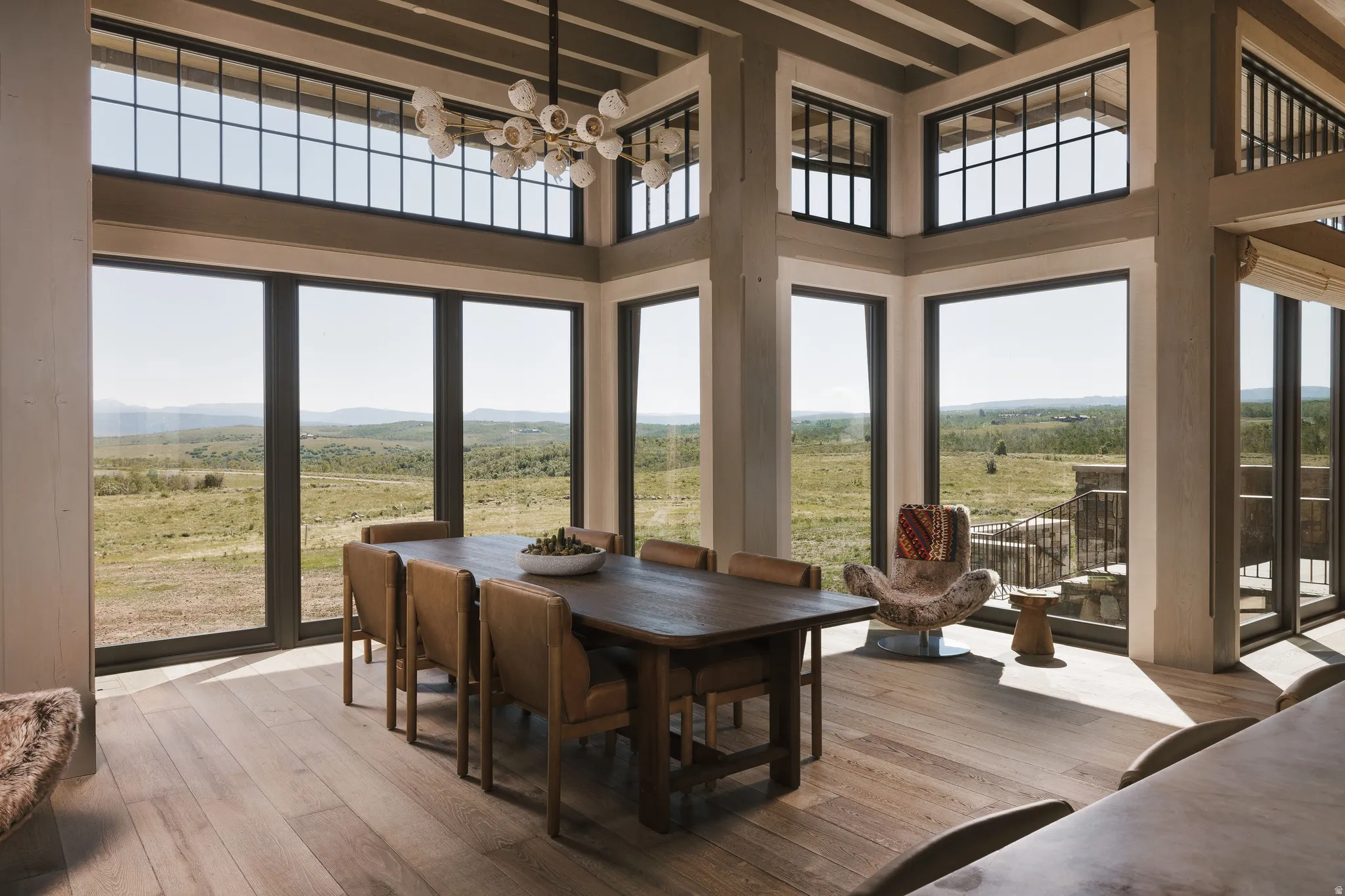 Dining area featuring expansive floor-to-ceiling windows, wood-finish flooring, and exposed ceiling beams