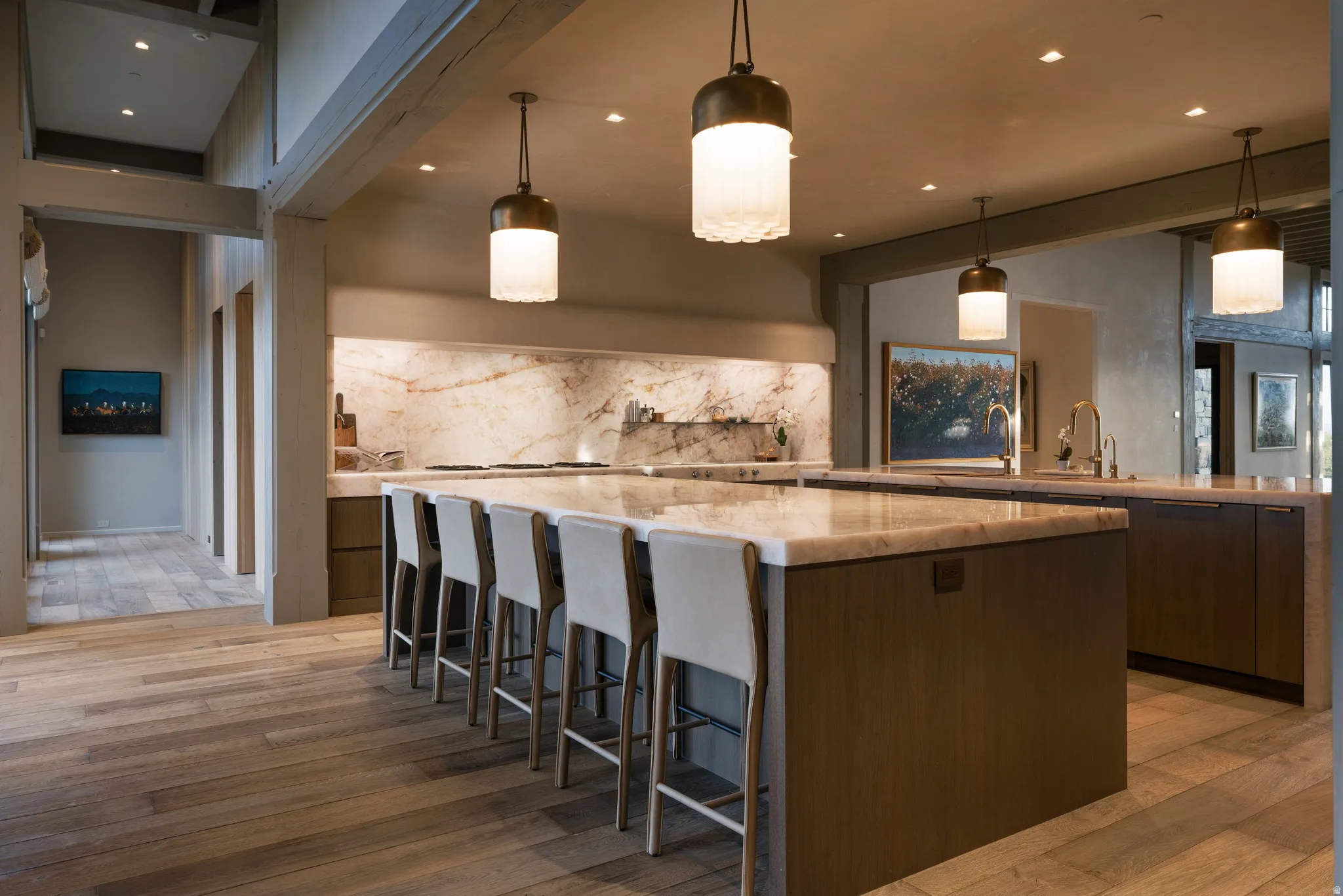 Spacious kitchen featuring a large central island with seating, stone countertops, integrated sink, and wood-finish flooring