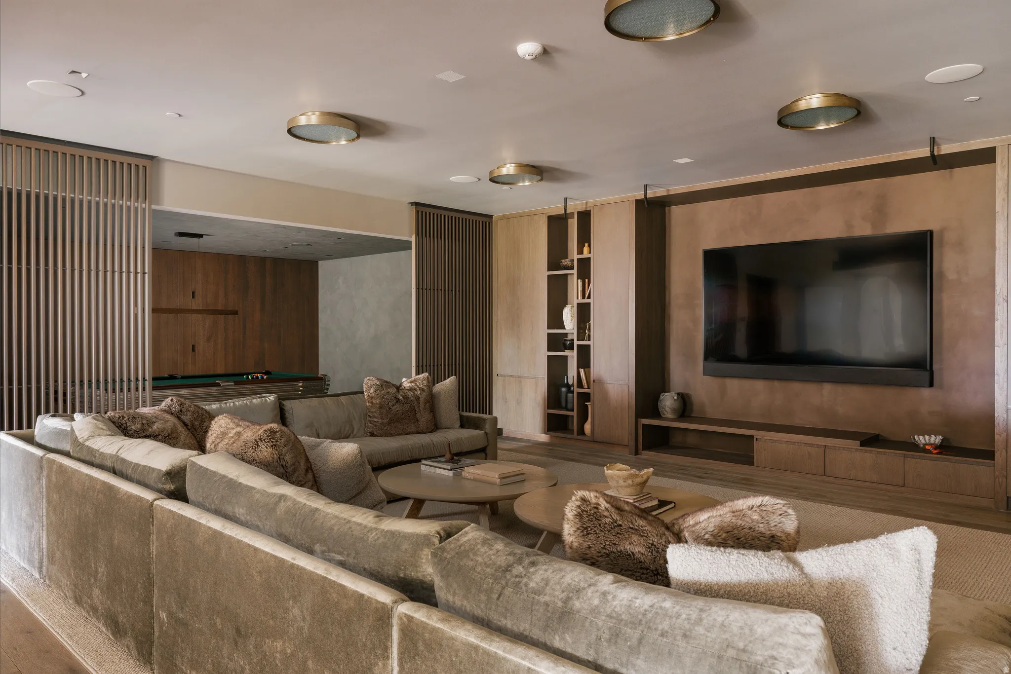 Open-concept living area featuring a large wall-mounted television, built-in entertainment console, integrated shelving, and recessed lighting fixtures