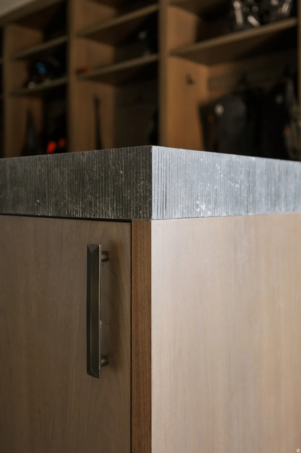 Textured countertop with wood-finish cabinetry and a dark bronze pull handle