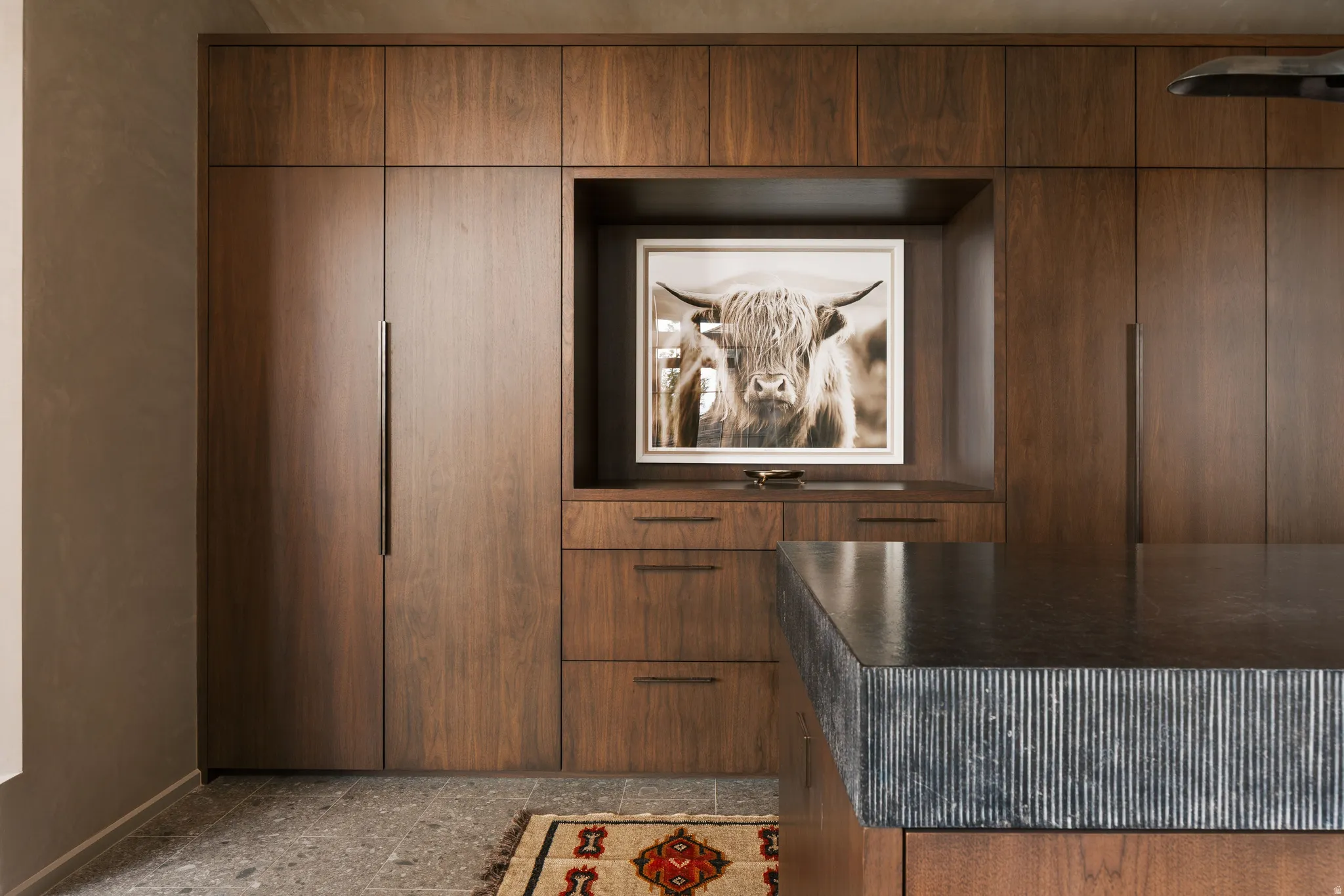 Integrated wood-panel cabinetry with recessed hardware, complemented by a large island featuring a fluted stone countertop