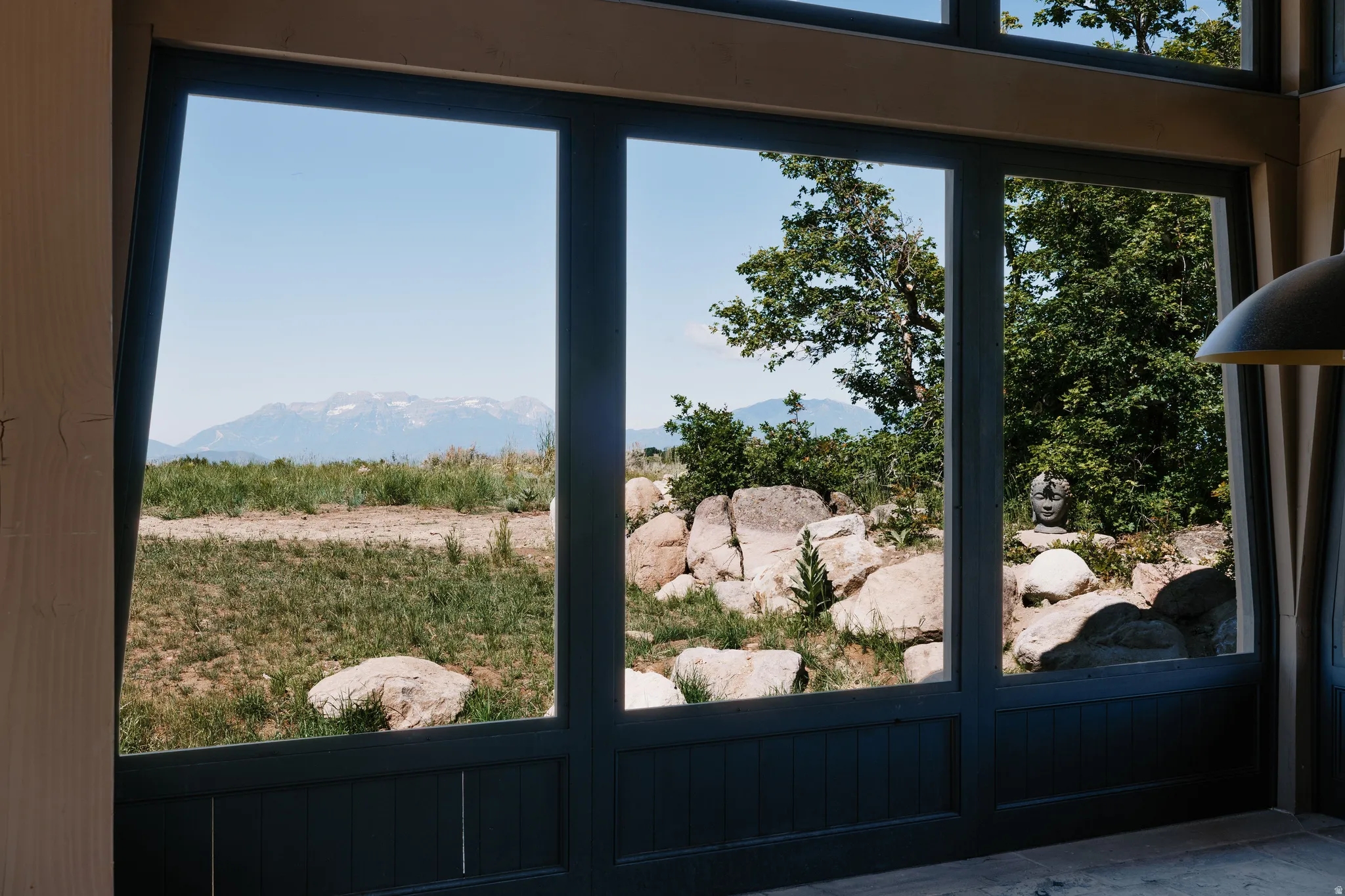 Expansive multi-pane windows with dark frames, offering mountain and natural landscape scenery