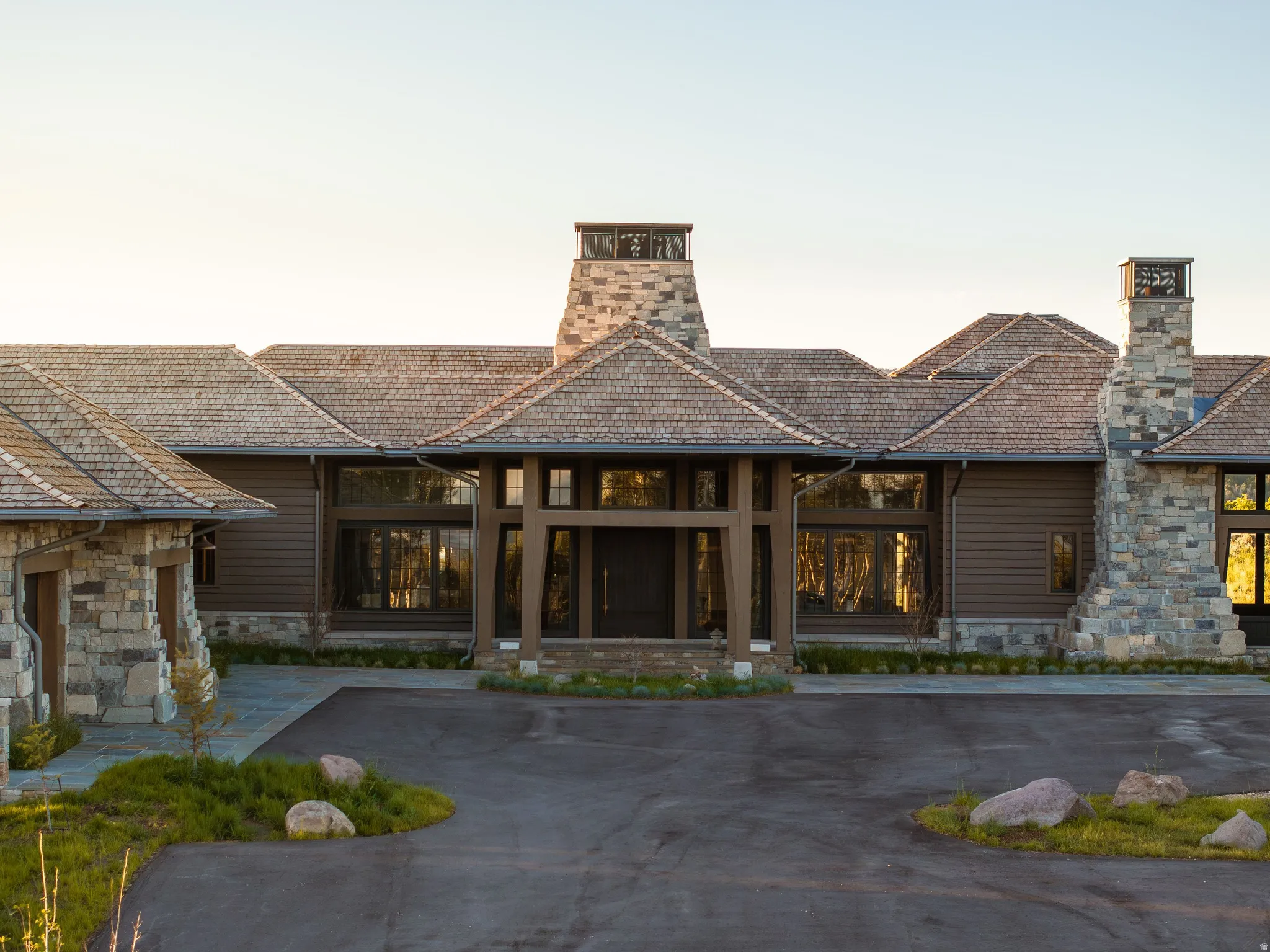 Contemporary residence featuring a split-pitch shingle roof, stone and horizontal siding exterior, and an expansive front entry with a covered portico