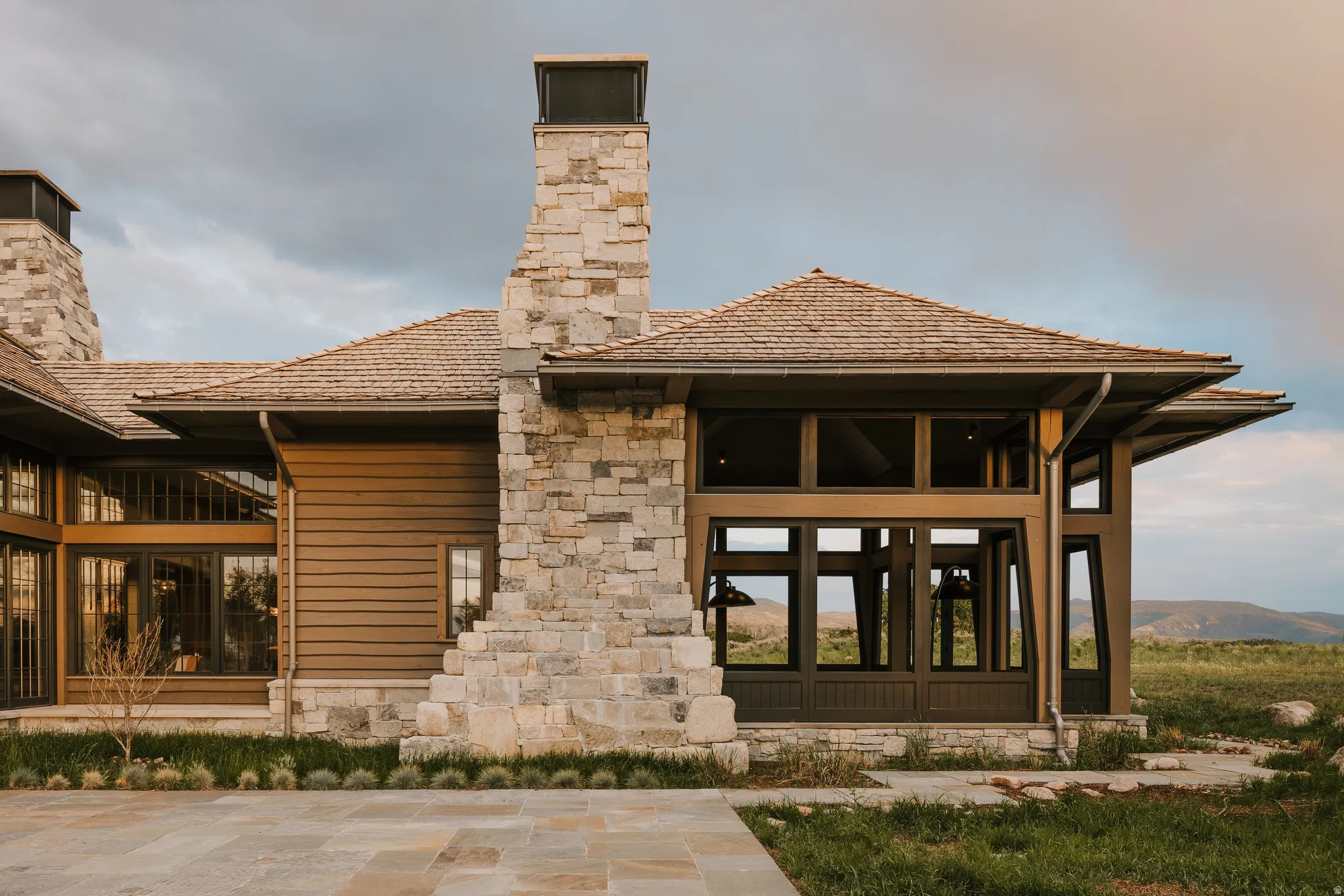 Contemporary architecture featuring a wood shake roof, stone chimneys, and expansive window walls