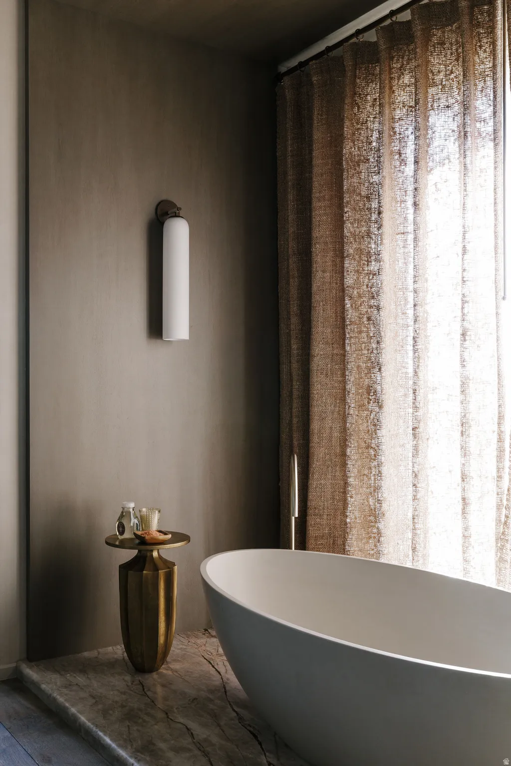 Freestanding soaking tub set on a marble-style floor platform