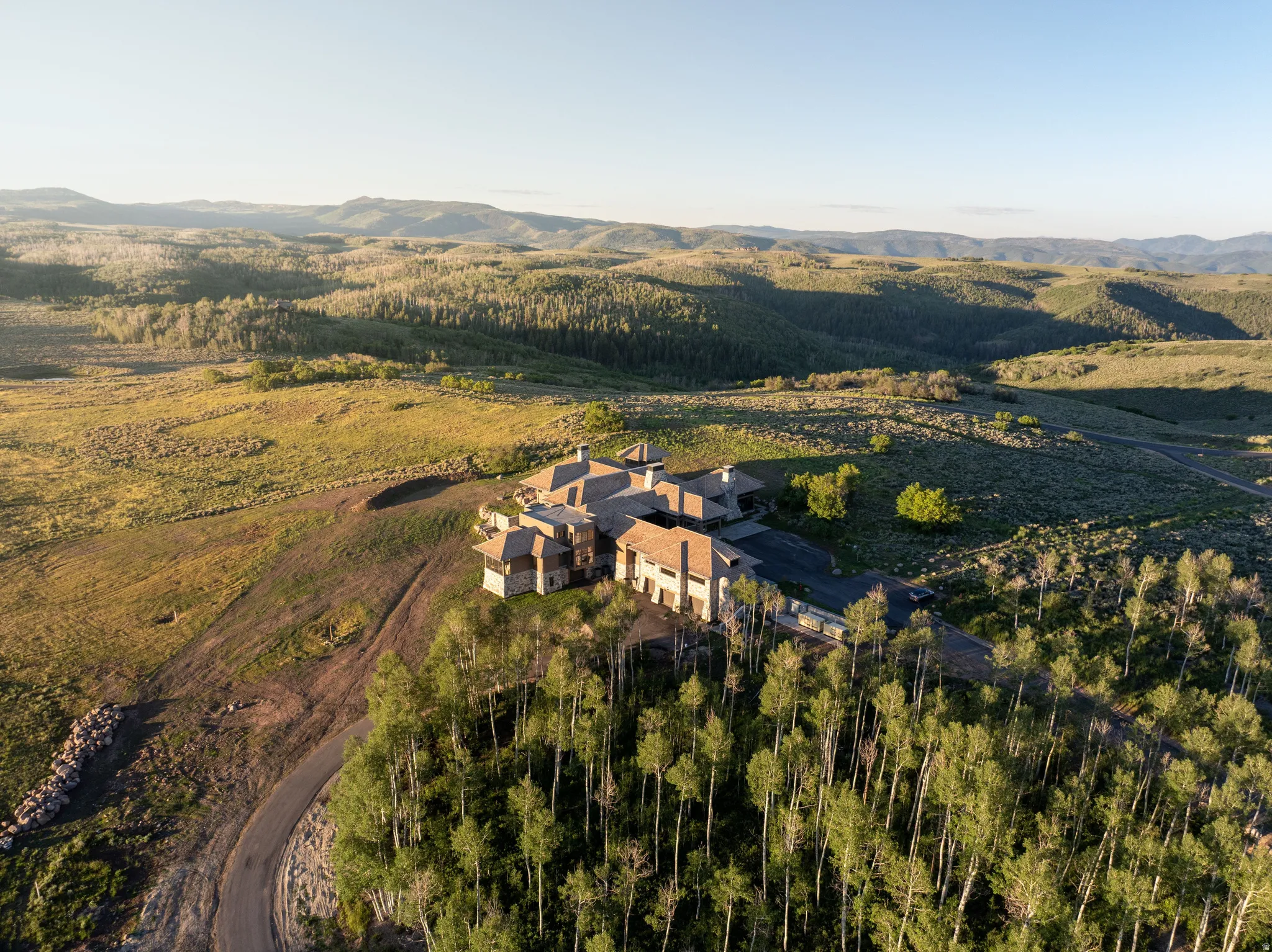 Expansive property featuring a multi-level residence with stone and stucco exterior, multiple chimneys, and a dark roof