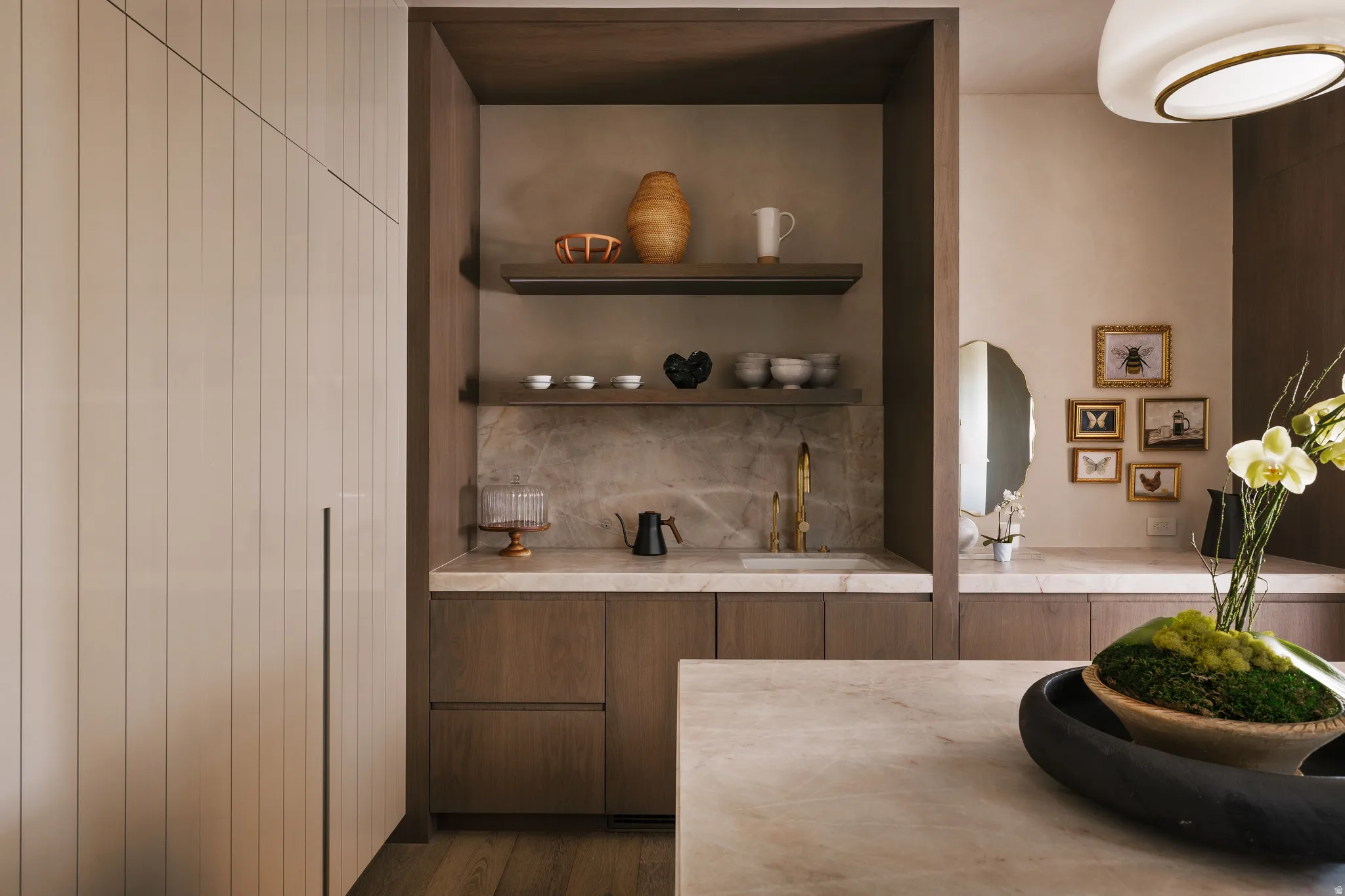 Built-in beverage station featuring a sink with a gold-tone faucet, open shelving, and a stone backsplash