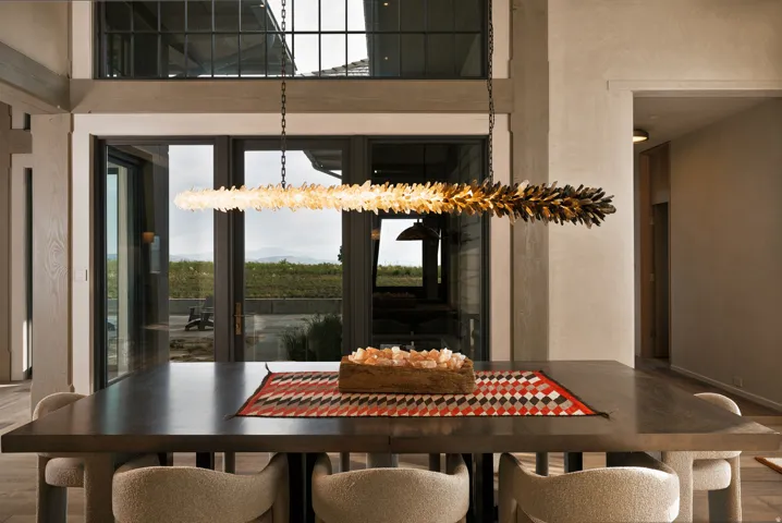 Dining area featuring a linear chandelier with a dual-tone finish, a dark-finish dining table, and light-toned walls