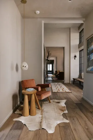Wide plank wood-finish flooring extending into an open hallway, accented by a distinctive pendant light fixture