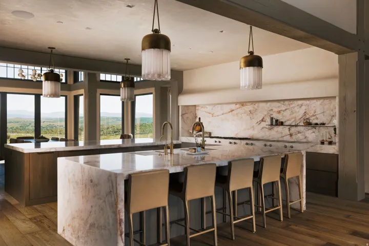 Kitchen featuring dual waterfall-edge islands, a stone slab backsplash, integrated range, and large windows