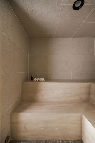Built-in stone bench with subtle veining, complemented by large format wall and ceiling tiles