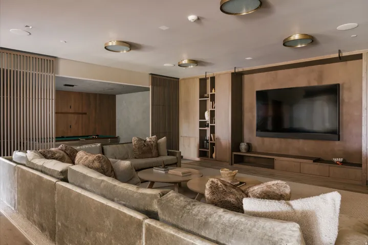 Open-concept living area featuring a large wall-mounted television, built-in entertainment console, integrated shelving, and recessed lighting fixtures